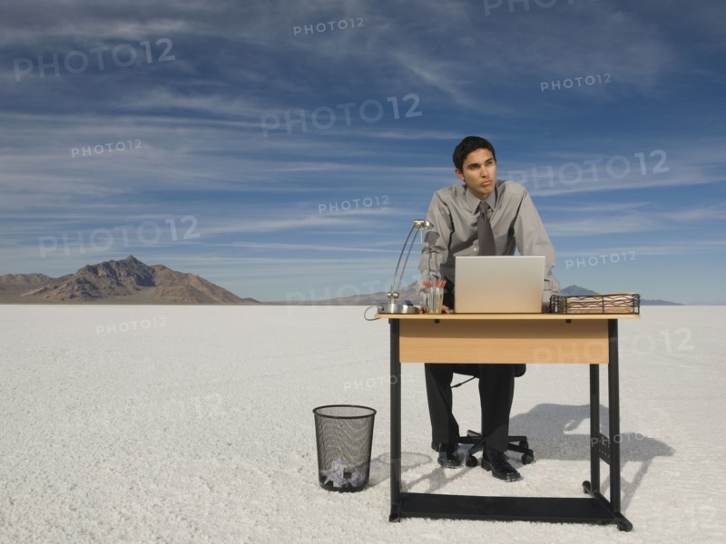 Hispanic businessman at desk on salt flats
