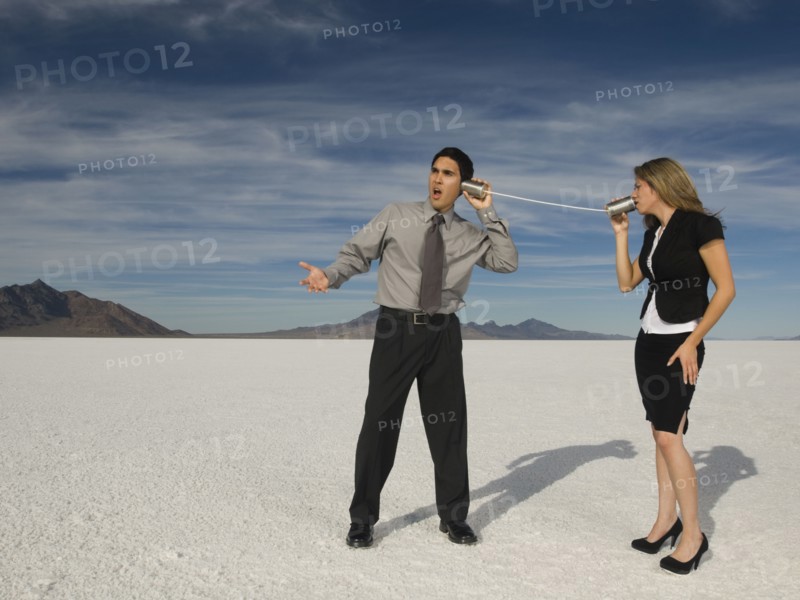 Hispanic businesspeople talking on can and string telephone