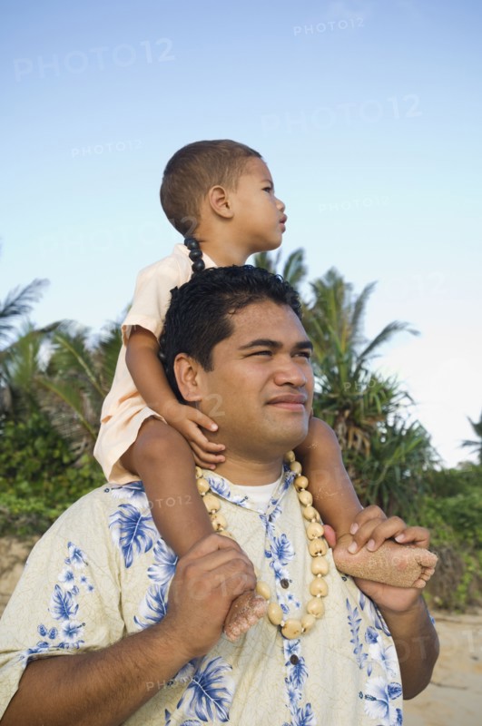 Pacific Islander father with son on shoulders at beach