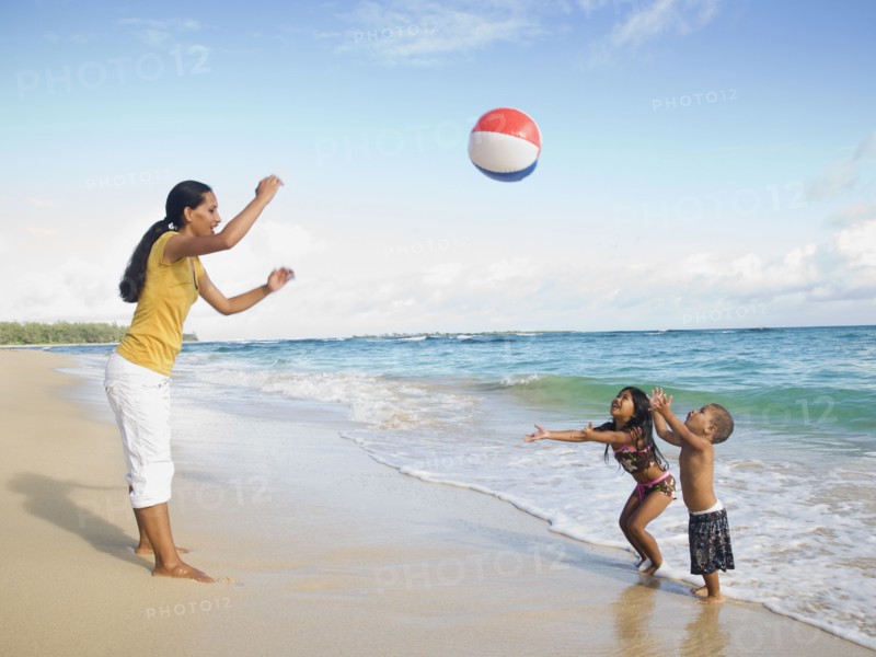 Pacific Islander mother and children playing with beach ball
