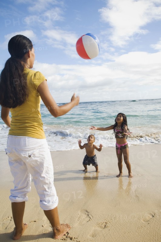 Pacific Islander mother and children playing with beach ball