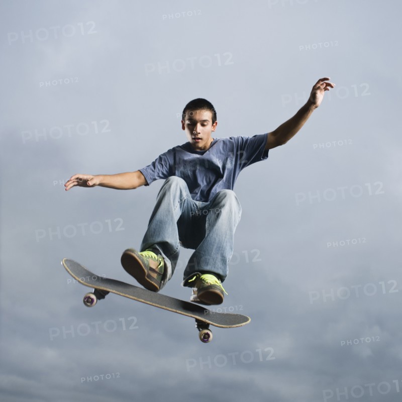 Mixed race teenager in mid-air on skateboard