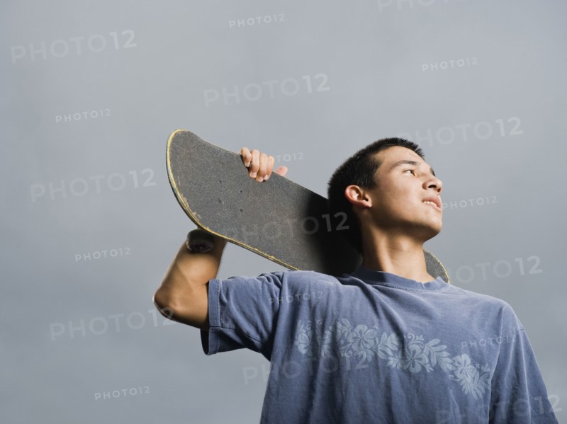 Mixed race teenager standing with skateboard
