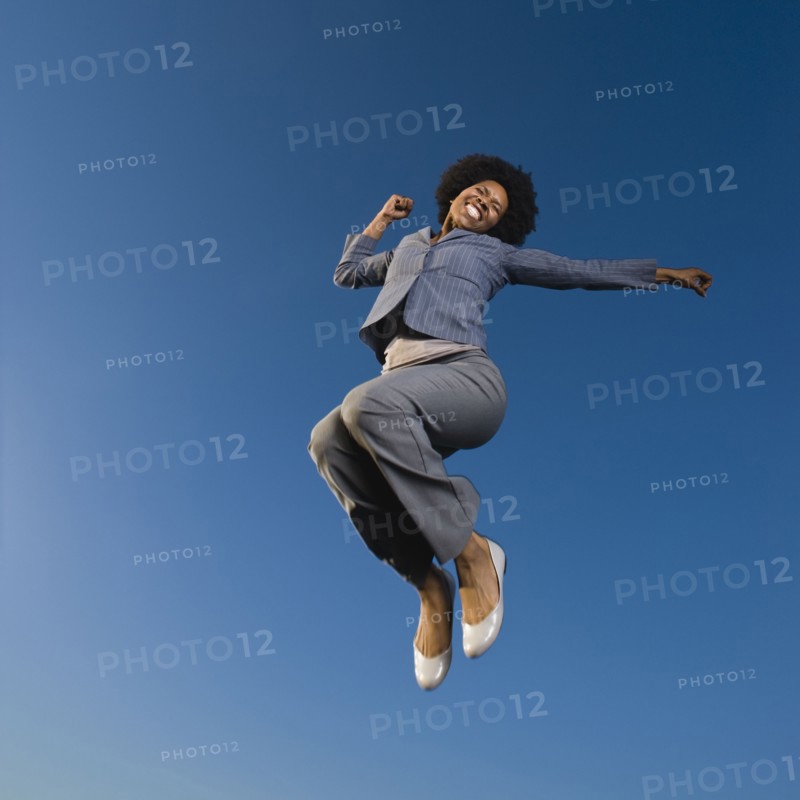 African businesswoman jumping in mid-air