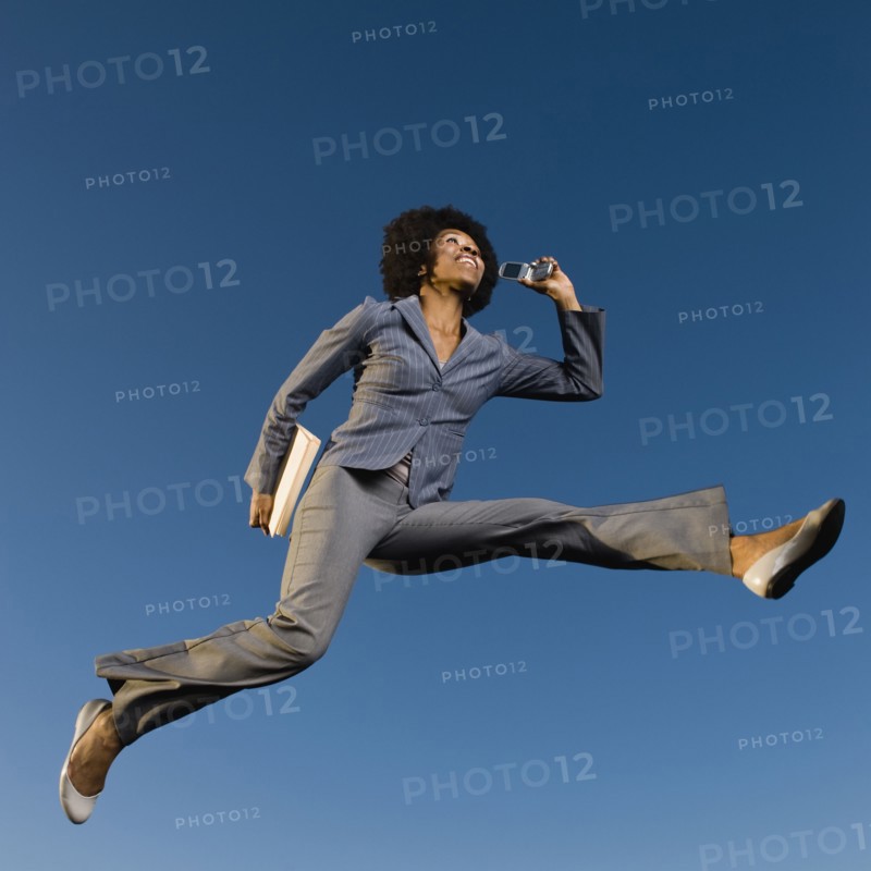 African businesswoman talking on cell phone in mid-air