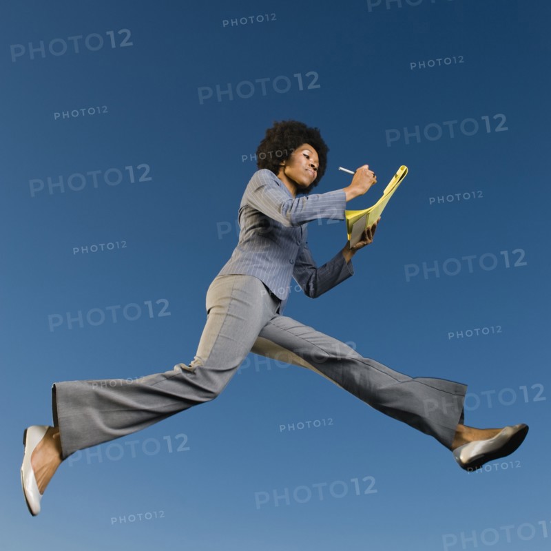 African businesswoman writing on legal pad in mid-air