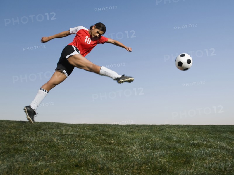 Mixed race woman kicking soccer ball