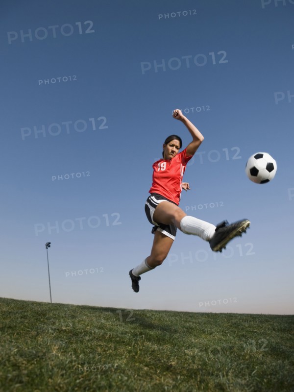 Mixed race woman kicking soccer ball