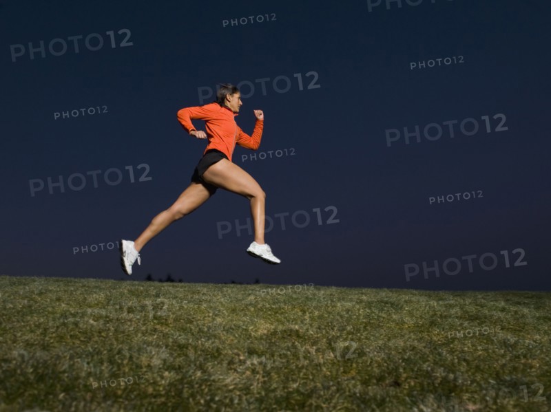 Mixed race woman running on grass