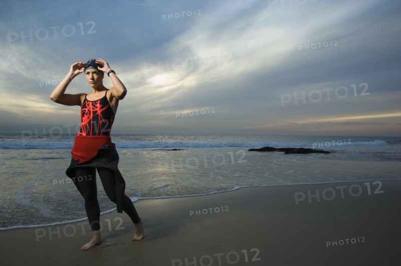 Hispanic woman in wetsuit on beach