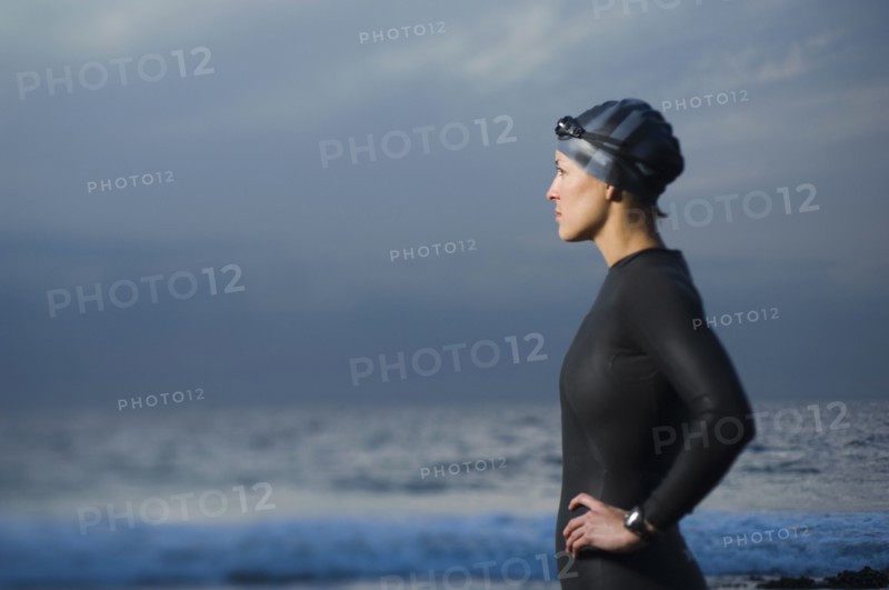 Hispanic woman in wetsuit on beach