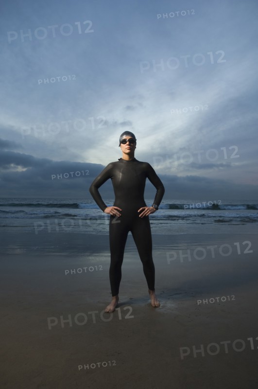 Hispanic woman in wetsuit on beach