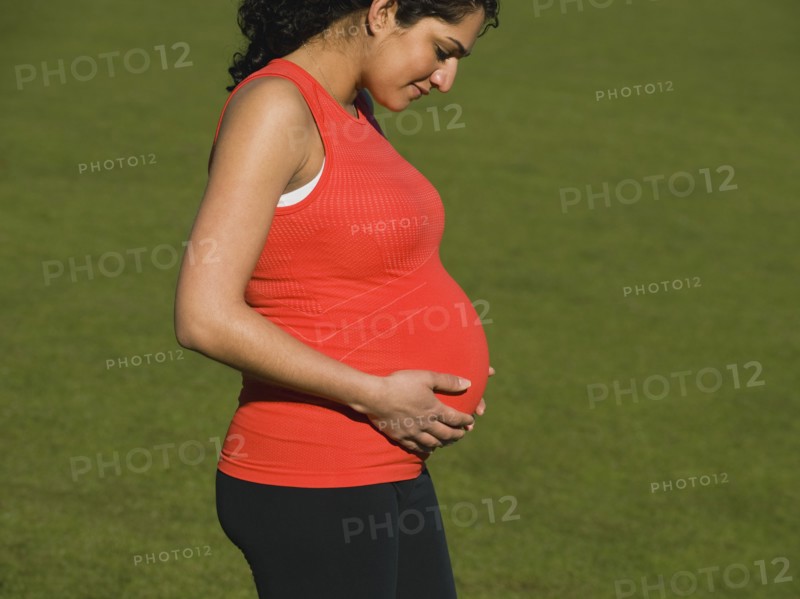 Pregnant Middle Eastern woman looking down at stomach