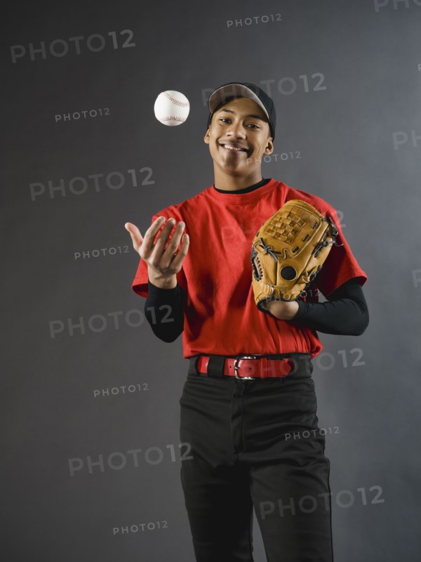 Mixed race baseball player tossing baseball