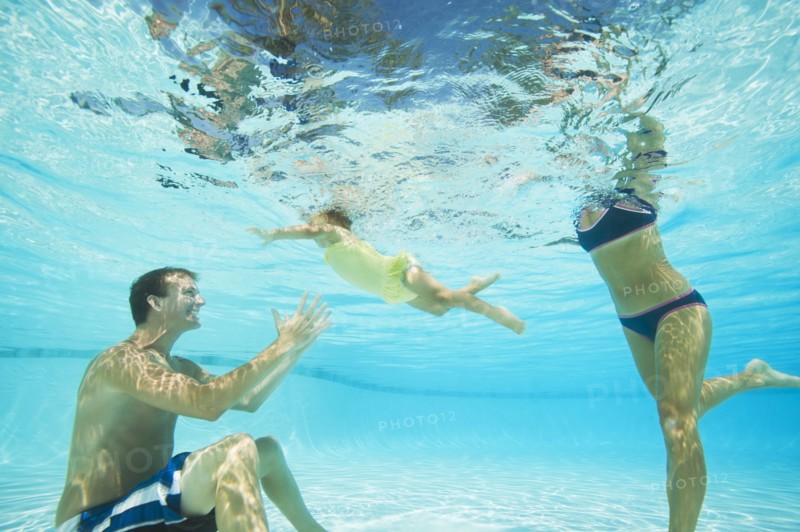 Parents swimming in swimming pool with daughter