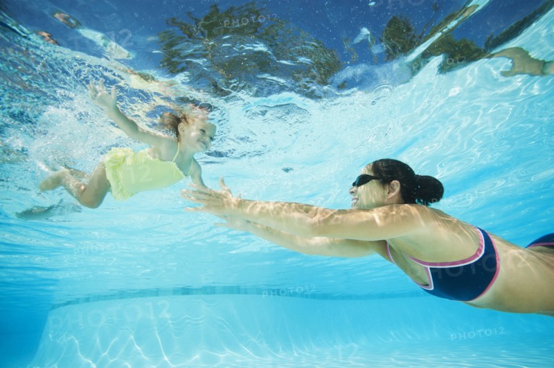 Mother swimming in swimming pool with daughter