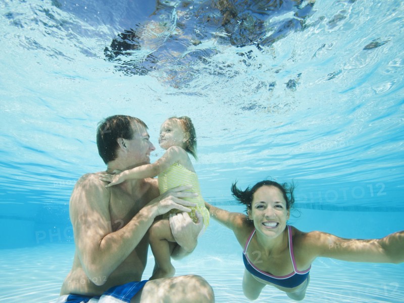 Parents swimming in swimming pool with daughter