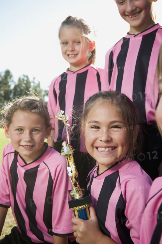 Smiling girl soccer players posing with trophy