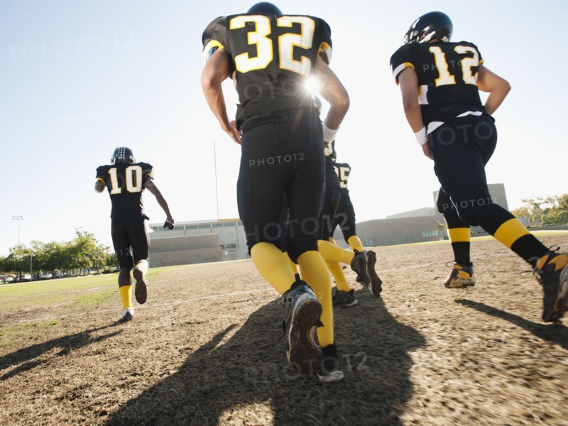Football players running on football field