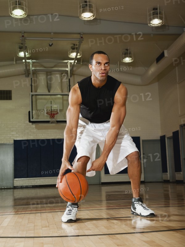 Mixed race man playing basketball on basketball court