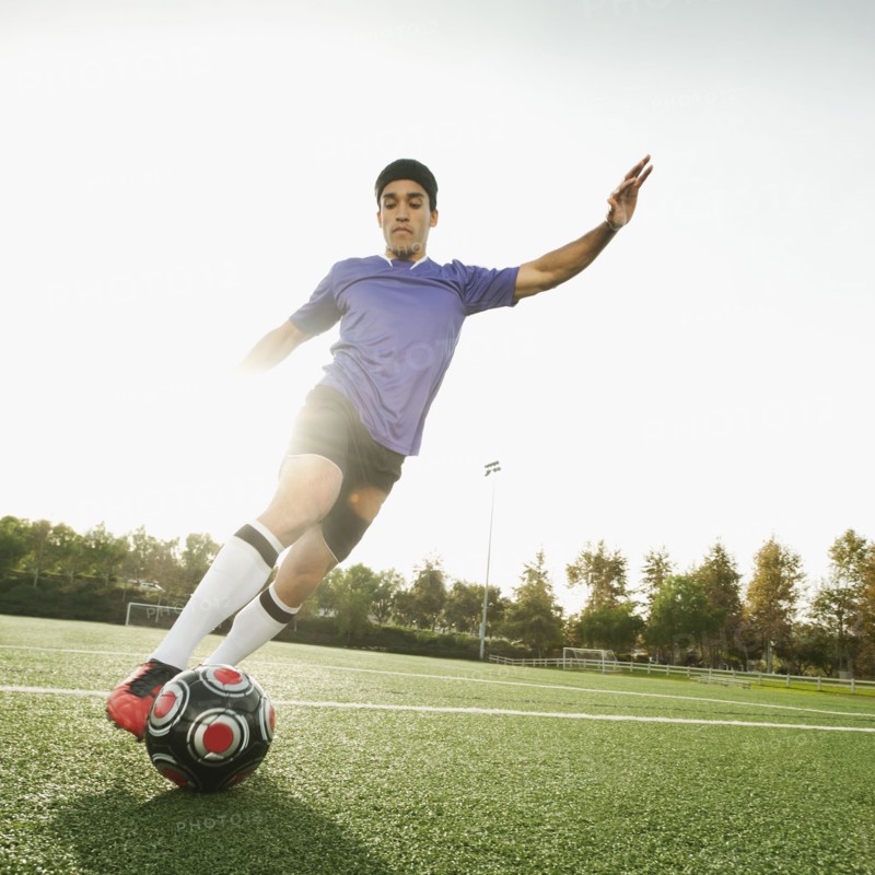 Mixed race soccer player kicking soccer ball