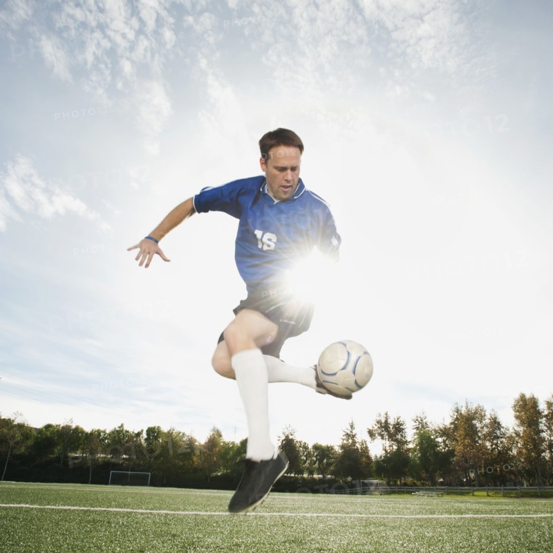 Caucasian soccer player kicking soccer ball