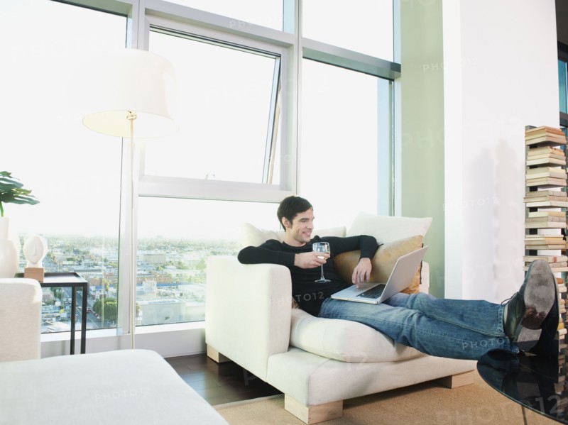 Man drinking wine and using laptop