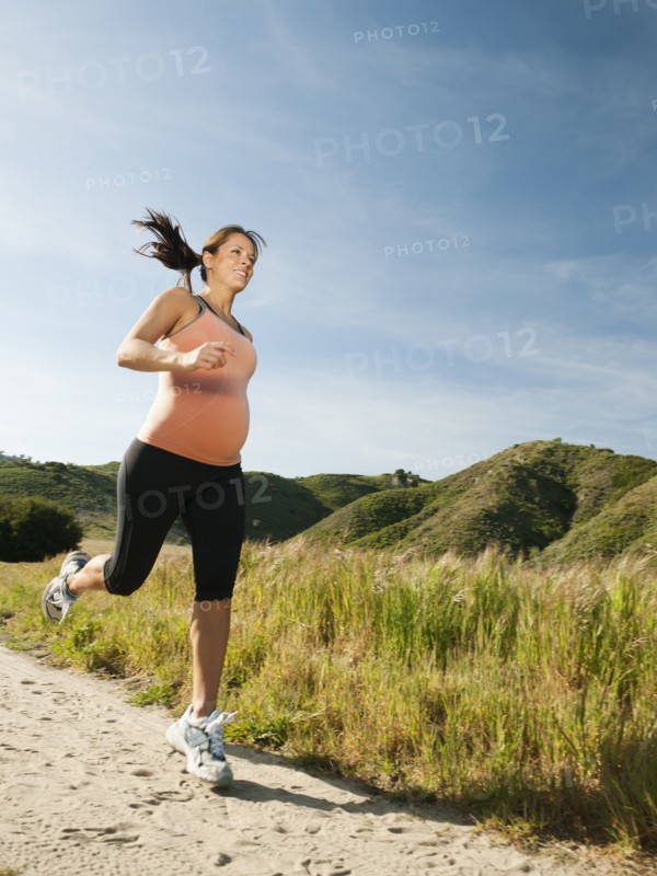 Pregnant Hispanic woman running in remote area