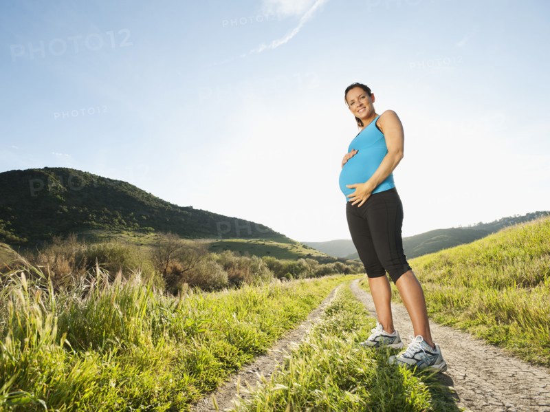 Pregnant Hispanic woman standing in remote area