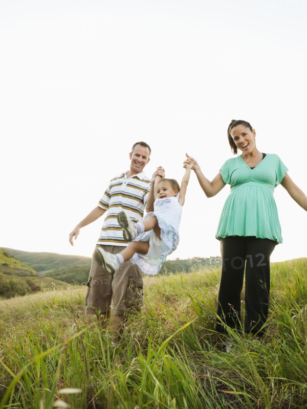Happy parents swinging daughter in field