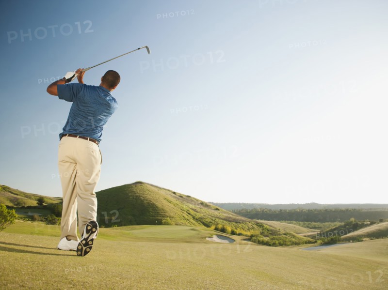 Black golfer swinging golf club
