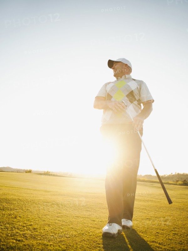 Caucasian man walking on golf course with golf club