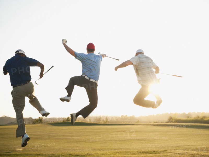 Excited golfers jumping in mid-air on golf course