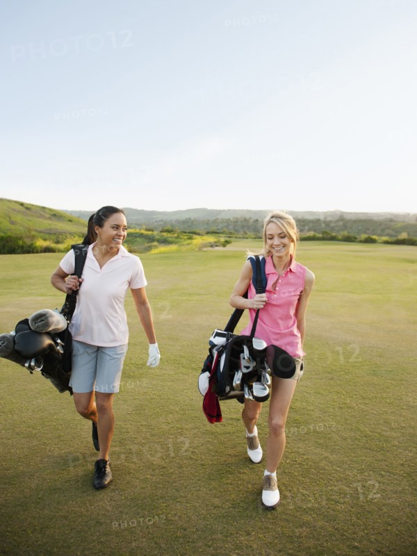 Women carrying golf bags on golf course