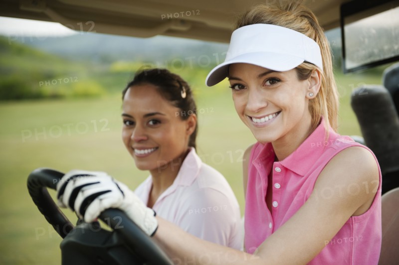 Women driving golf cart on golf course