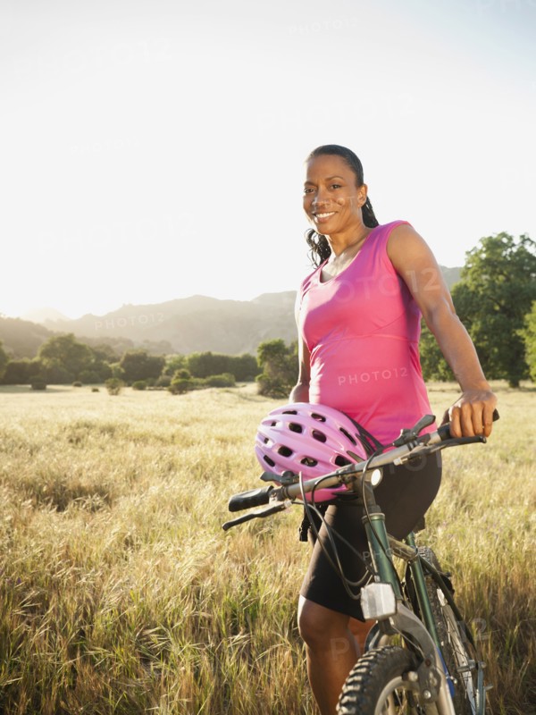 Black biker standing with mountain bike