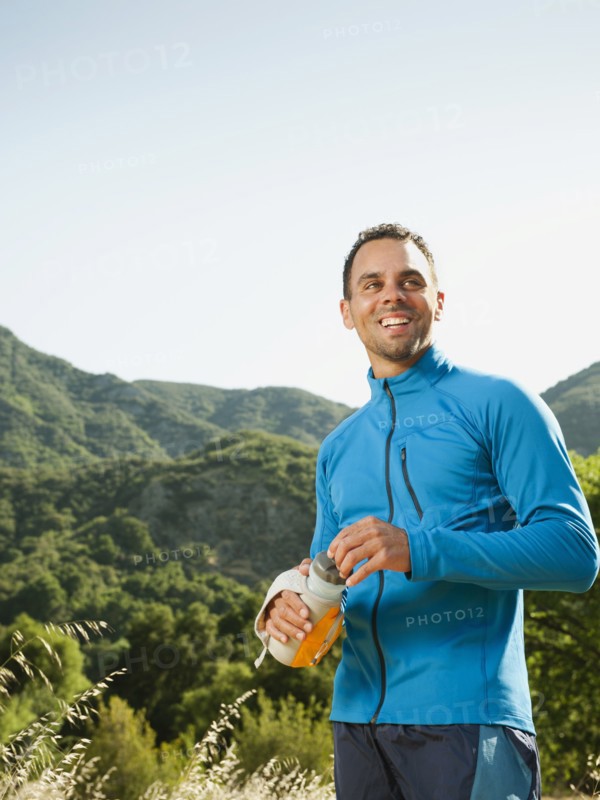 Athletic mixed race man drinking water outdoors