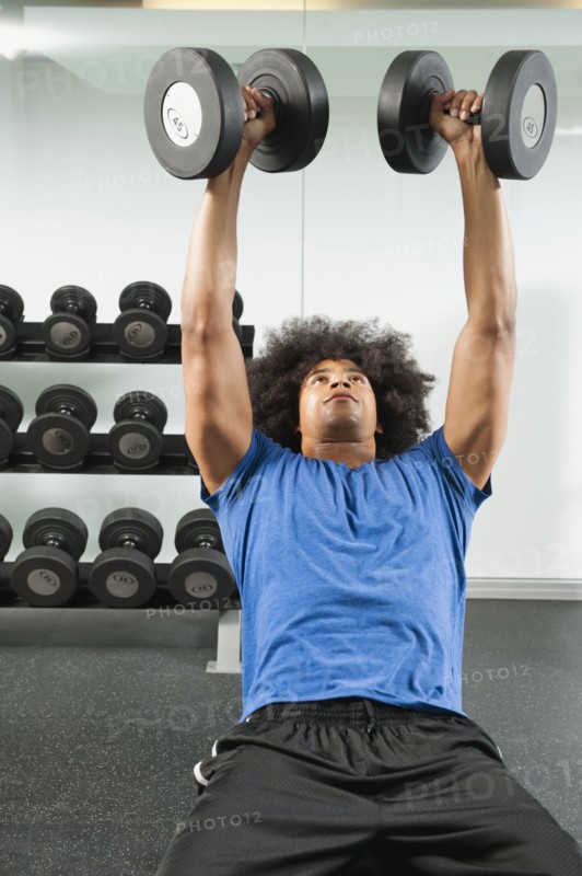 Black man lifting dumbbells in gym
