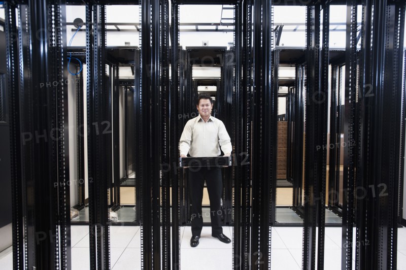 Asian businessman standing in empty server room