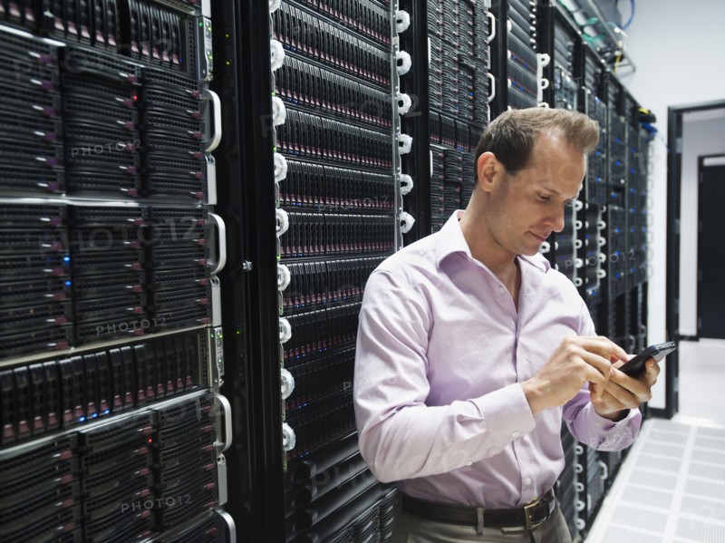 Caucasian businessman using cell phone in server room