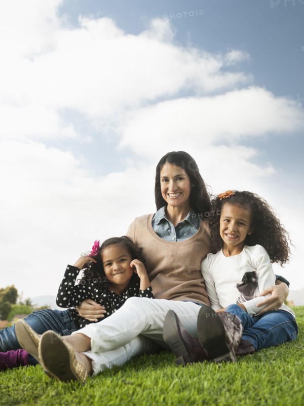 Mother and daughters sitting in grass