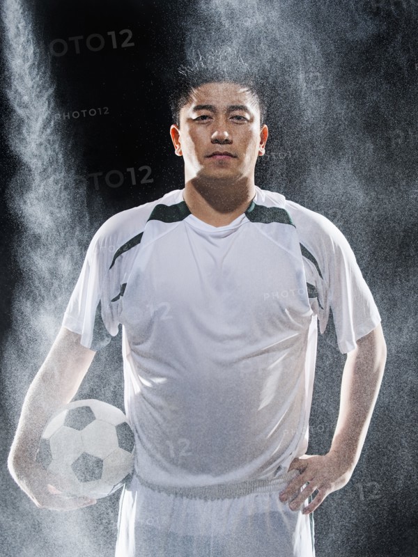 Asian soccer player standing in rain