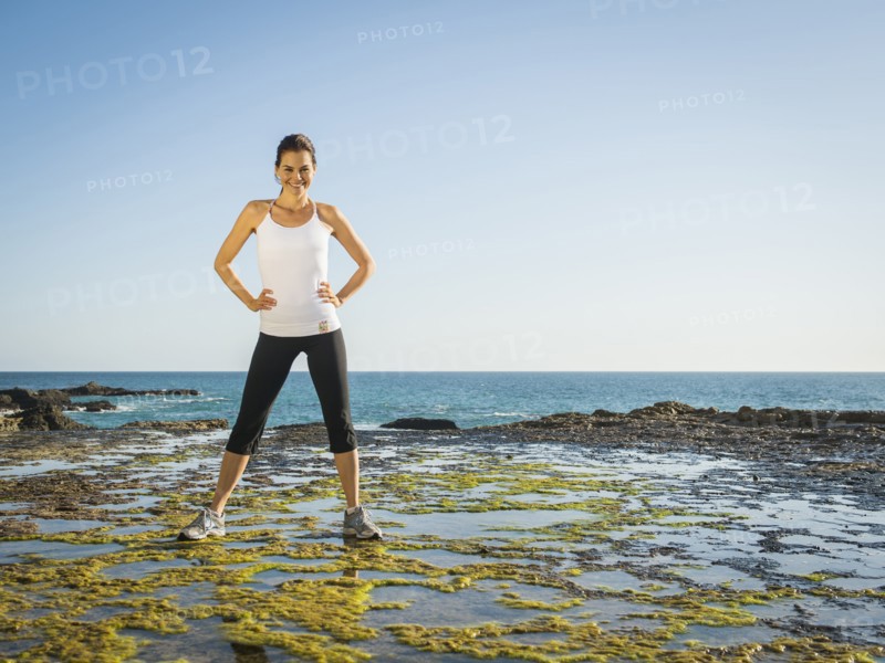 Mixed race runner standing on rocky beach