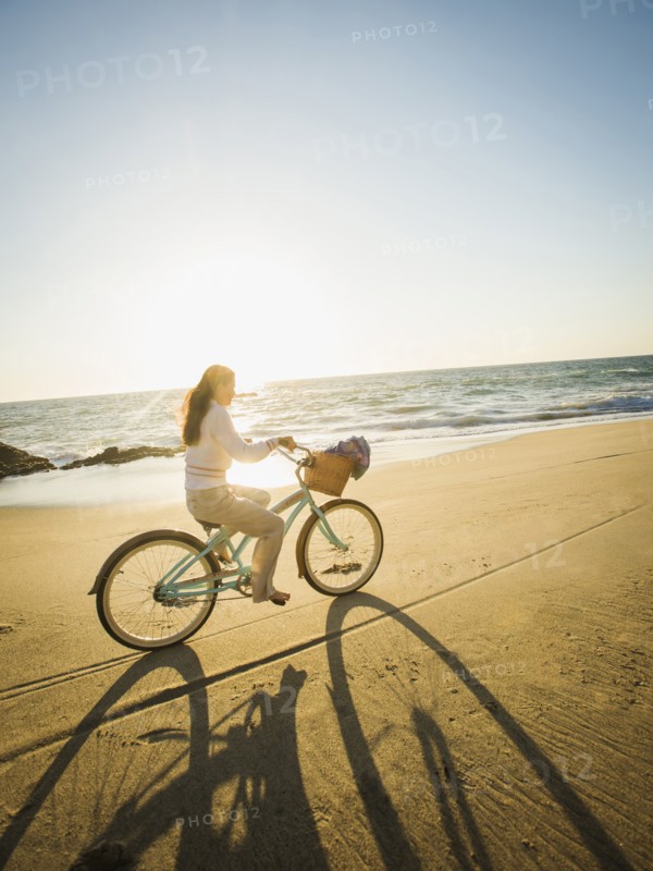Mixed race woman riding bicycle on beach