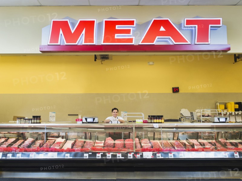 Hispanic butcher at meat counter of grocery store