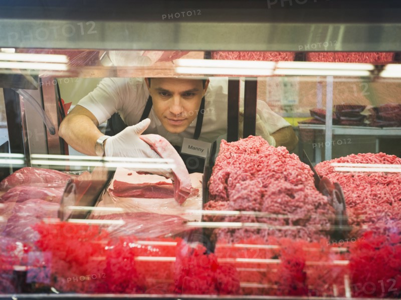 Hispanic butcher at meat counter of grocery store
