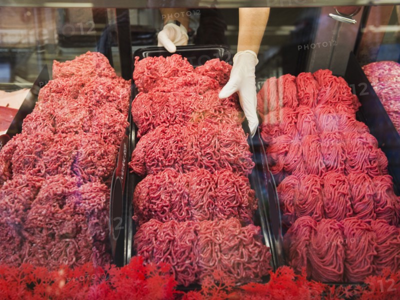 Hispanic butcher at meat counter of grocery store