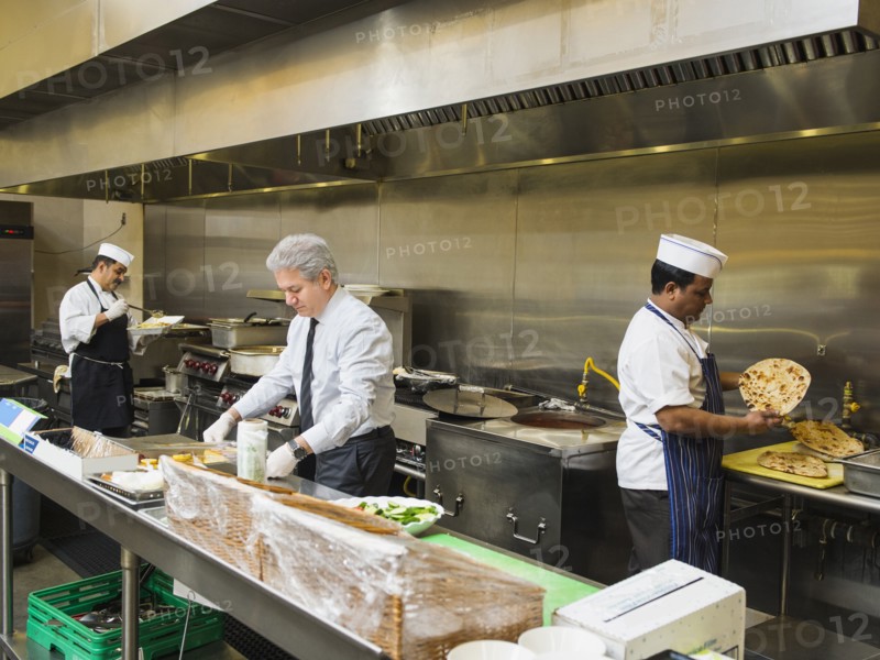 Businessman and chefs working in kitchen