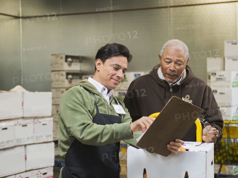 Workers using clipboard in walk-in freezer