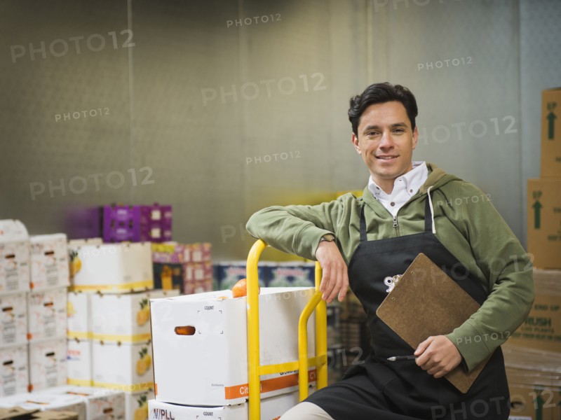 Hispanic worker carting boxes in walk-in freezer
